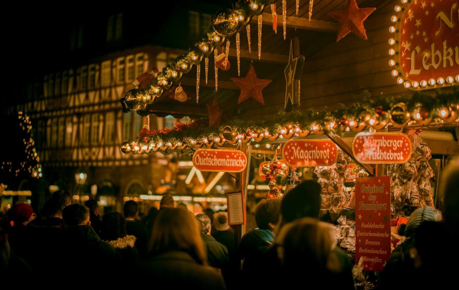 Gäste am beleuchteten Weihnachtsmarkt am Abend