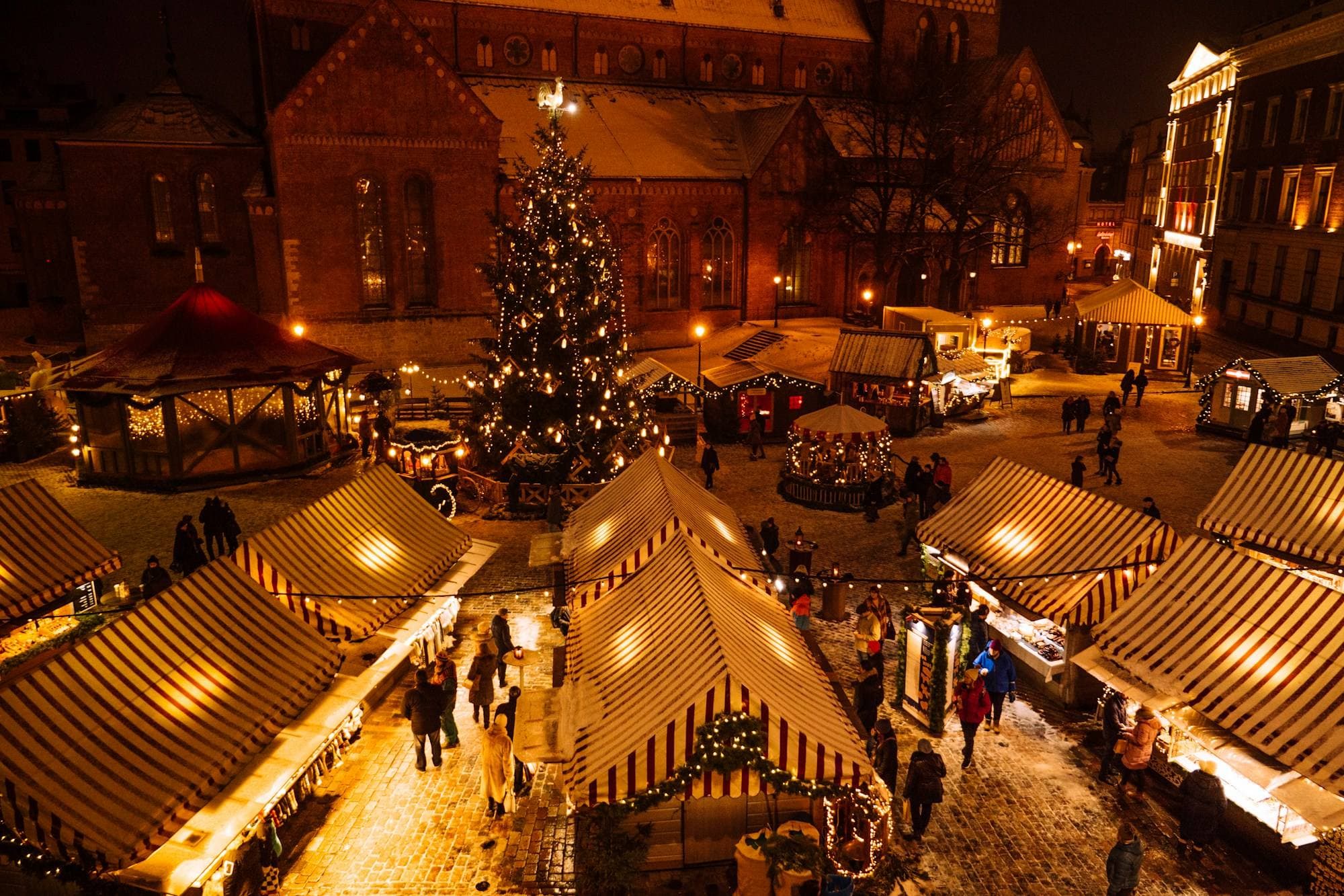 Weihnachtsmarkt bei Nacht mit beleuchtetem Baum und Ständen