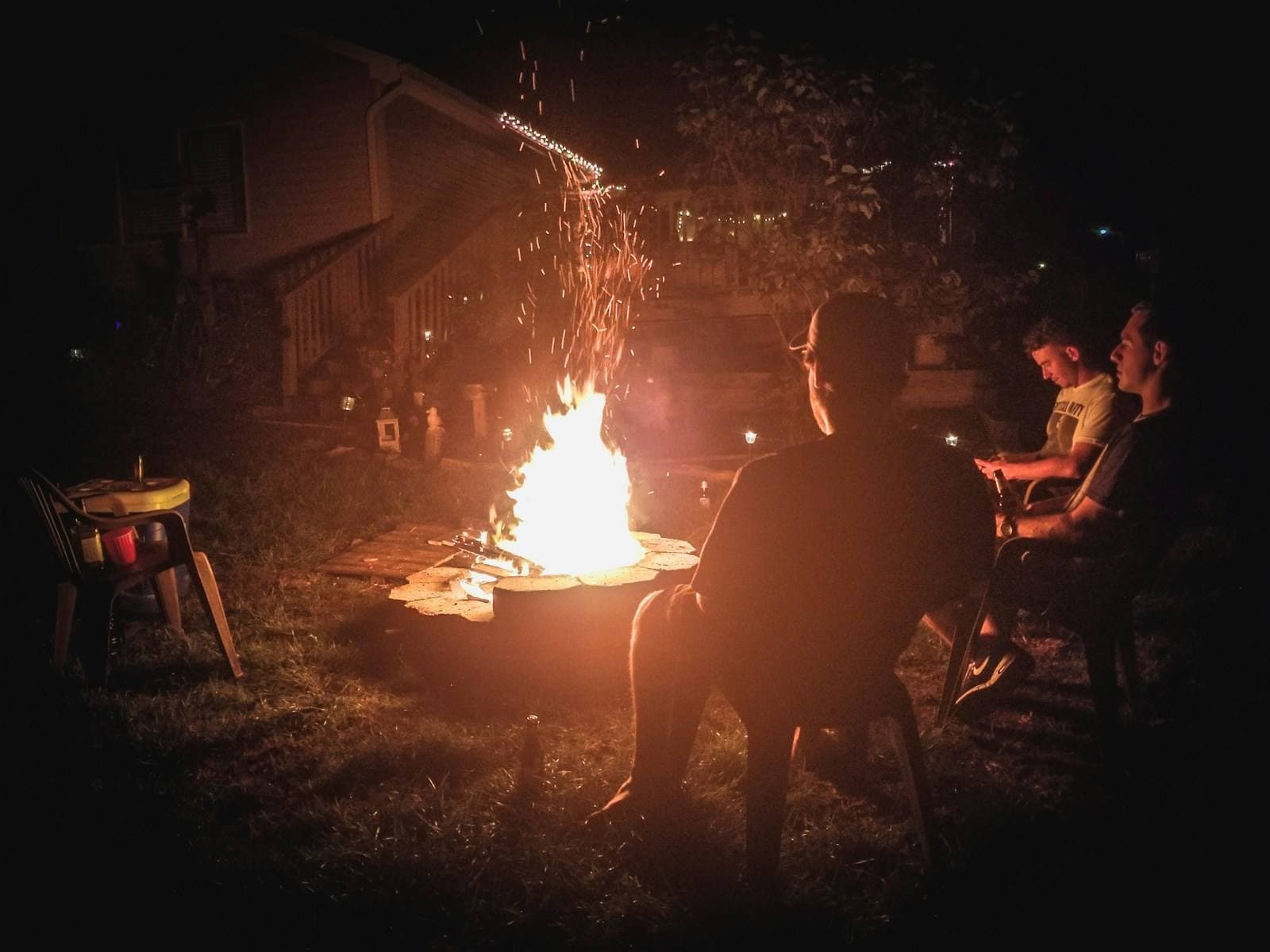 Gäste sitzen nachts an einer Feuerstelle