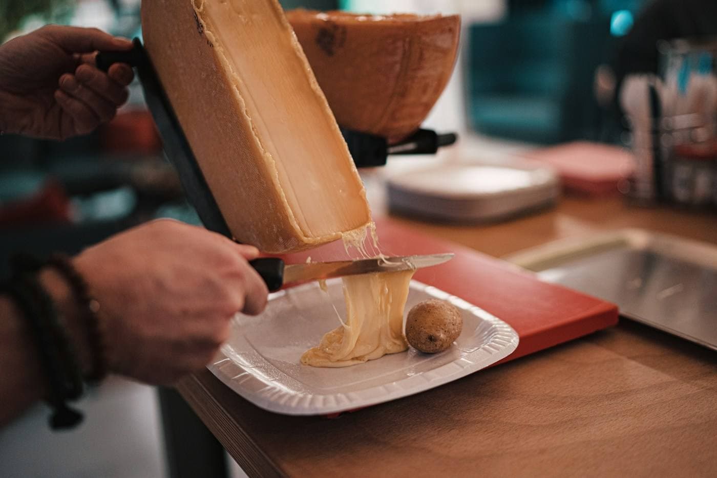 Geschmolzener Raclette-Käse wird auf einen Teller gestrichen